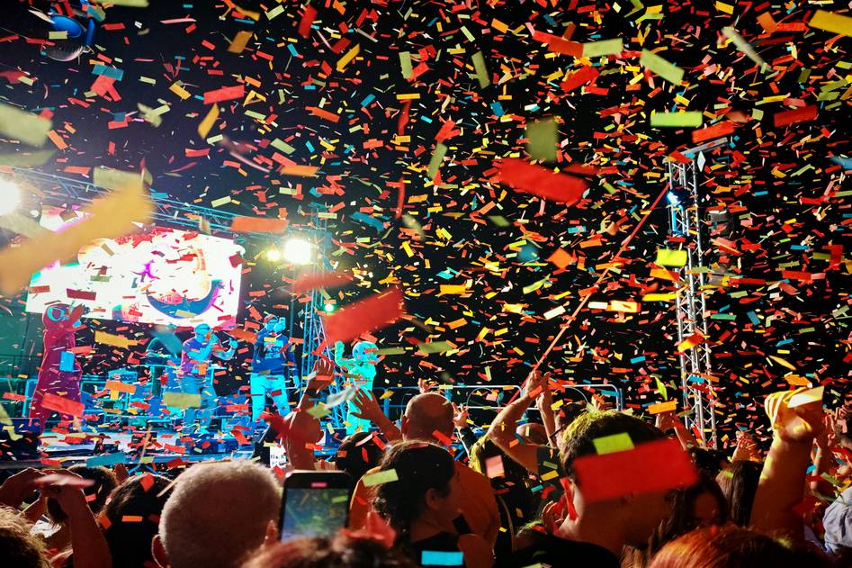K-Pop group performing on stage with vibrant lights and energetic crowd